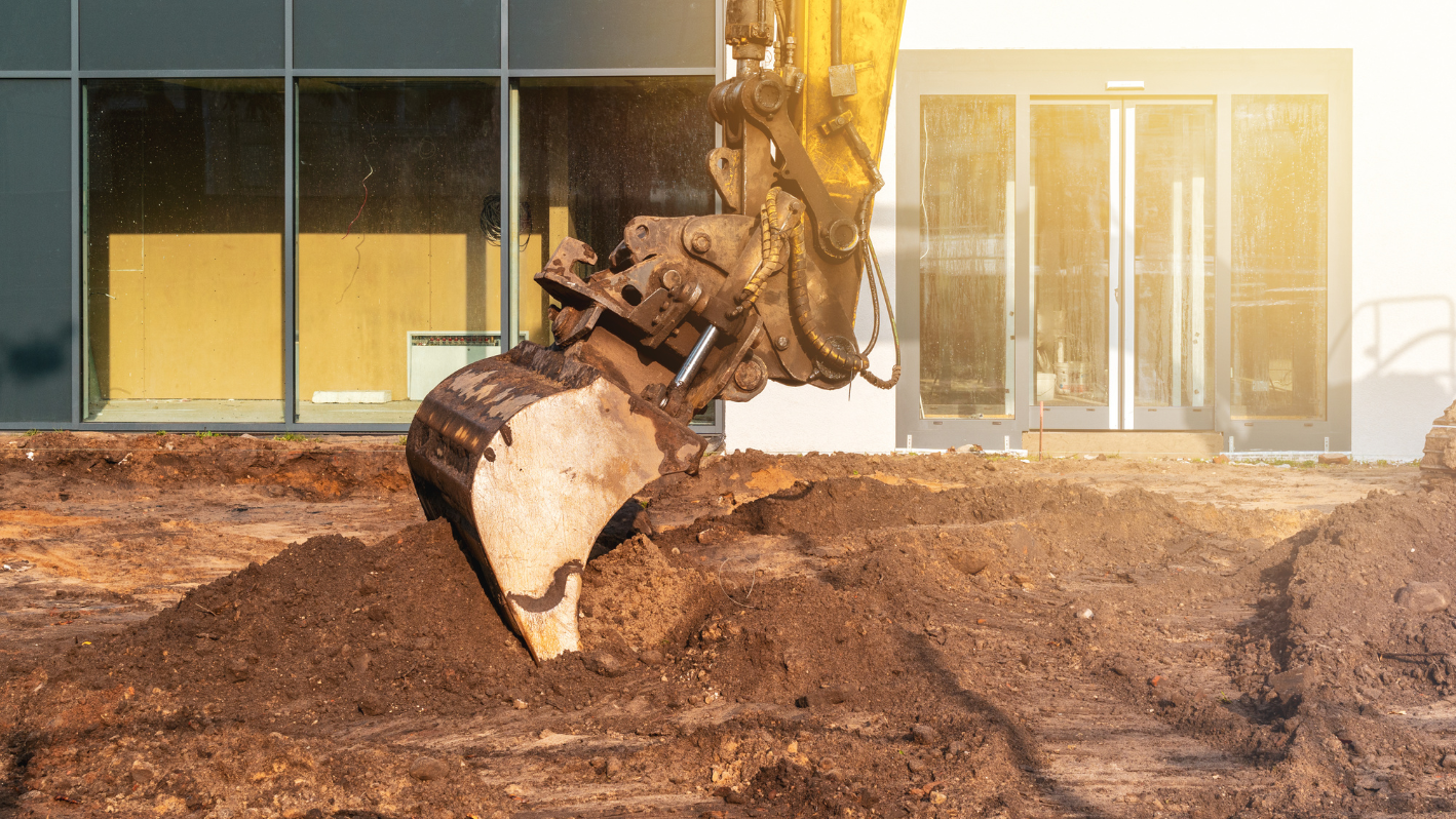 A bulldozer digging dirt in front of a building