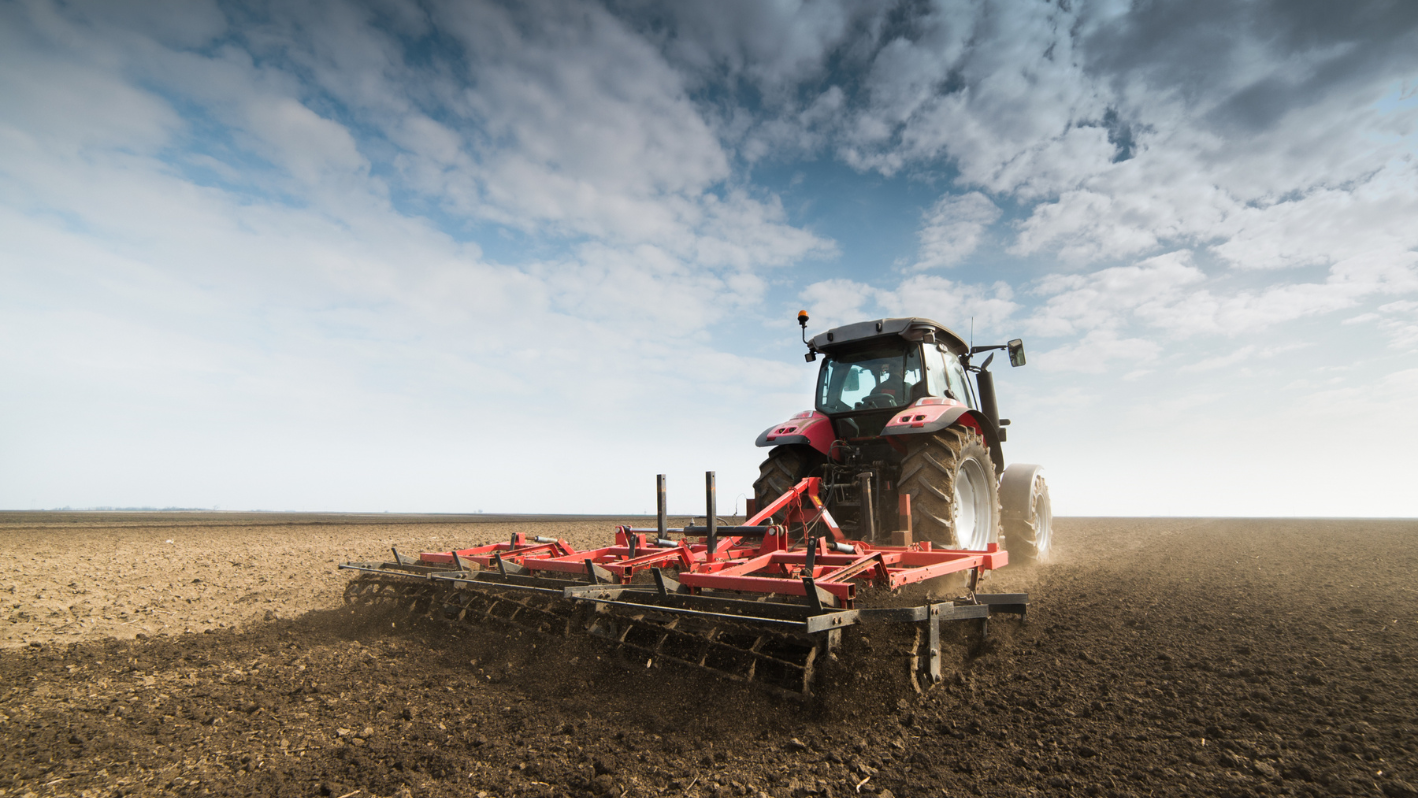 A tractor is plowing a field on a cloudy day