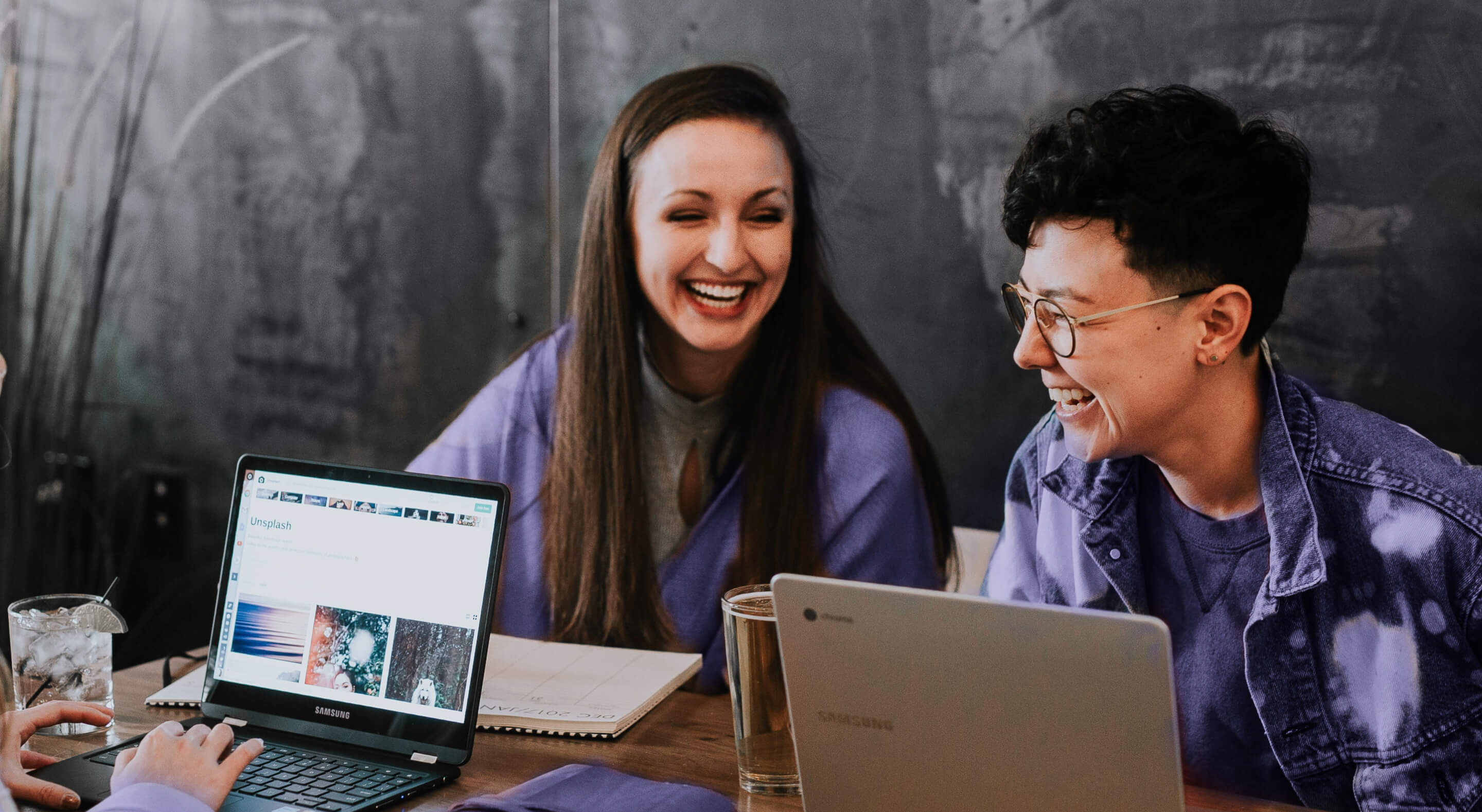 A group of people sitting around a table with laptops